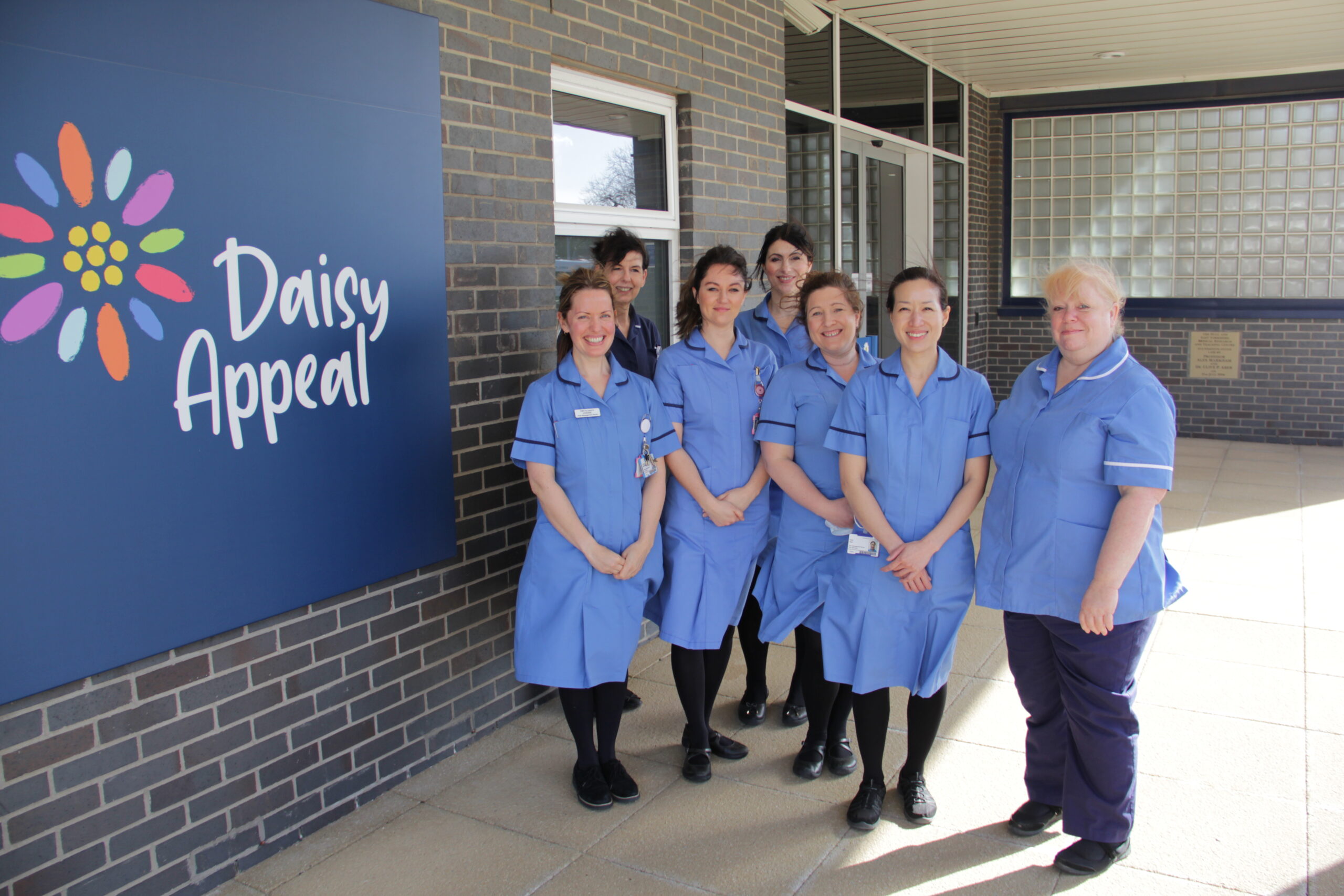 Nurses standing next to a sign saying Daisy Appeal