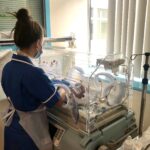 A picture of a nurse turning their back to the camera, looking over at the new NICU Specialist cot.